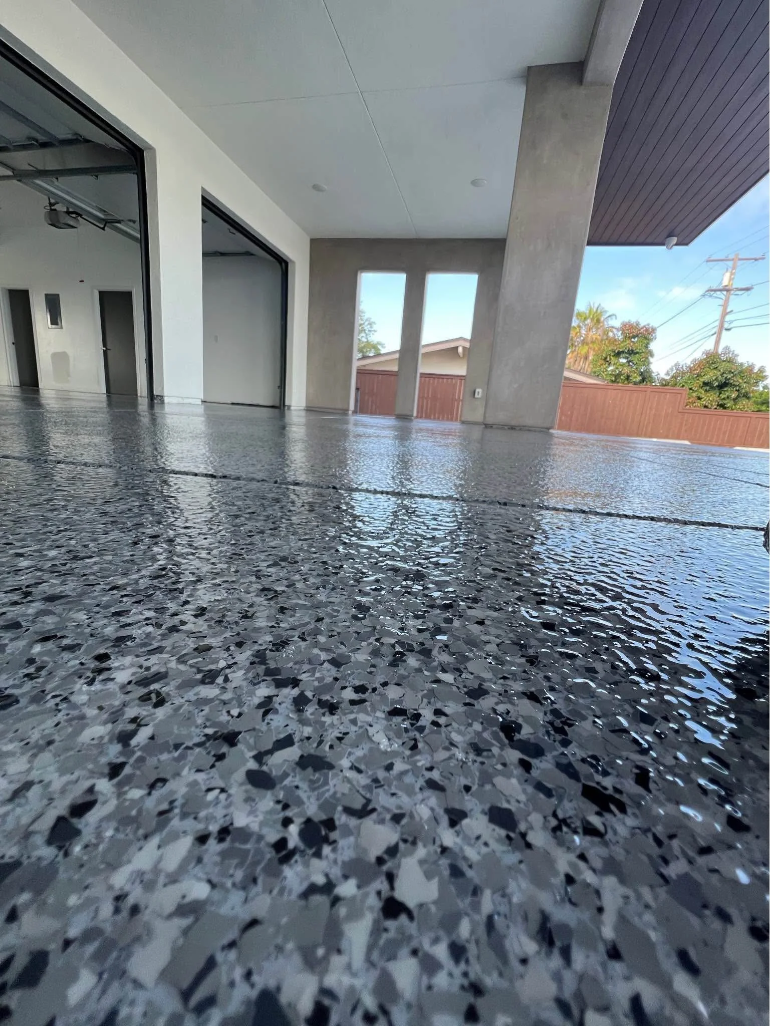Indoor-outdoor patio with flake epoxy floor and glass folding doors in custom home
